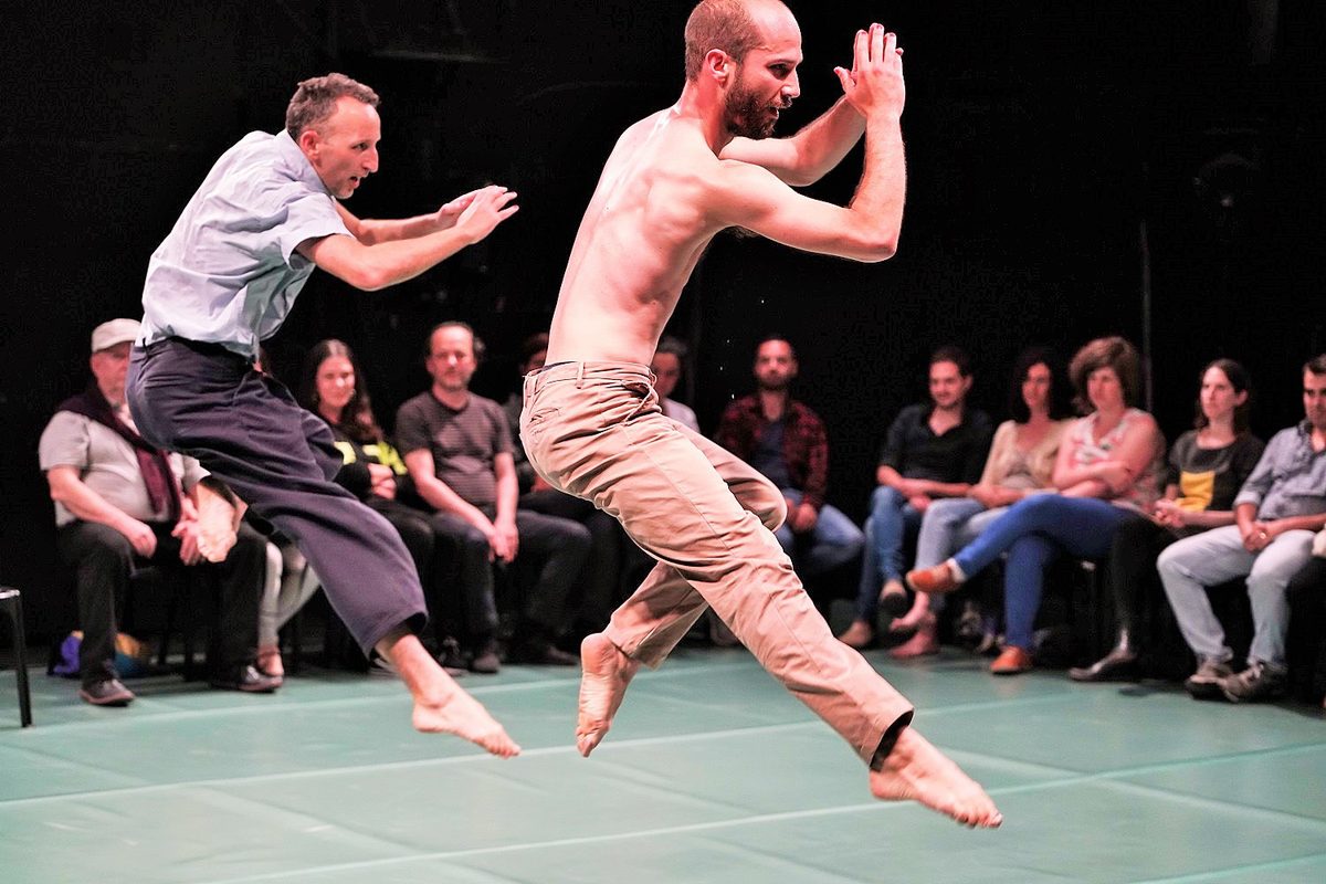 Tal and another dancer jumping in the middle of a seated audience